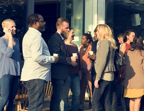 Summit attendees gathering around each other drinking coffee